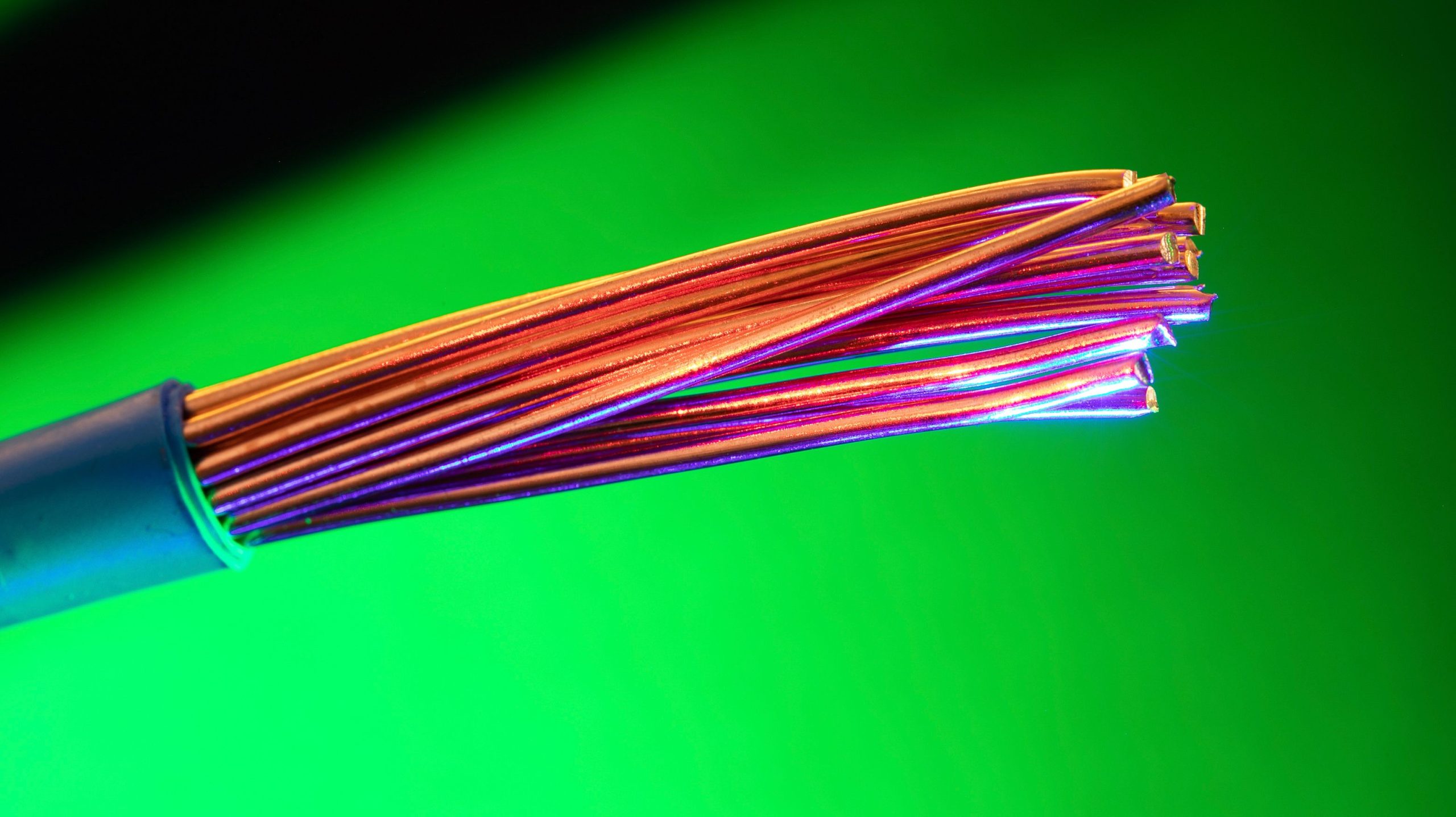 Fils cuivre colorés sur fond vert vibrant.