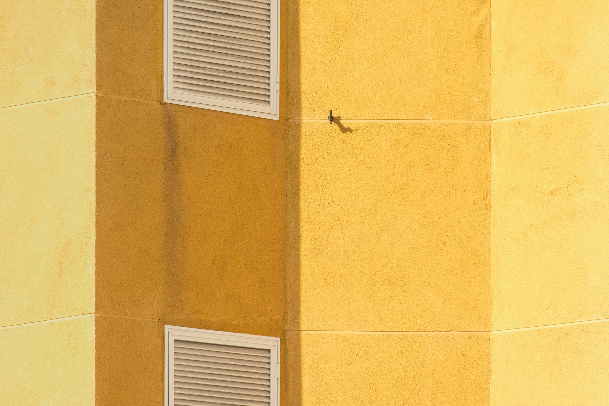 Angle de bâtiment jaune avec grilles de ventilation
