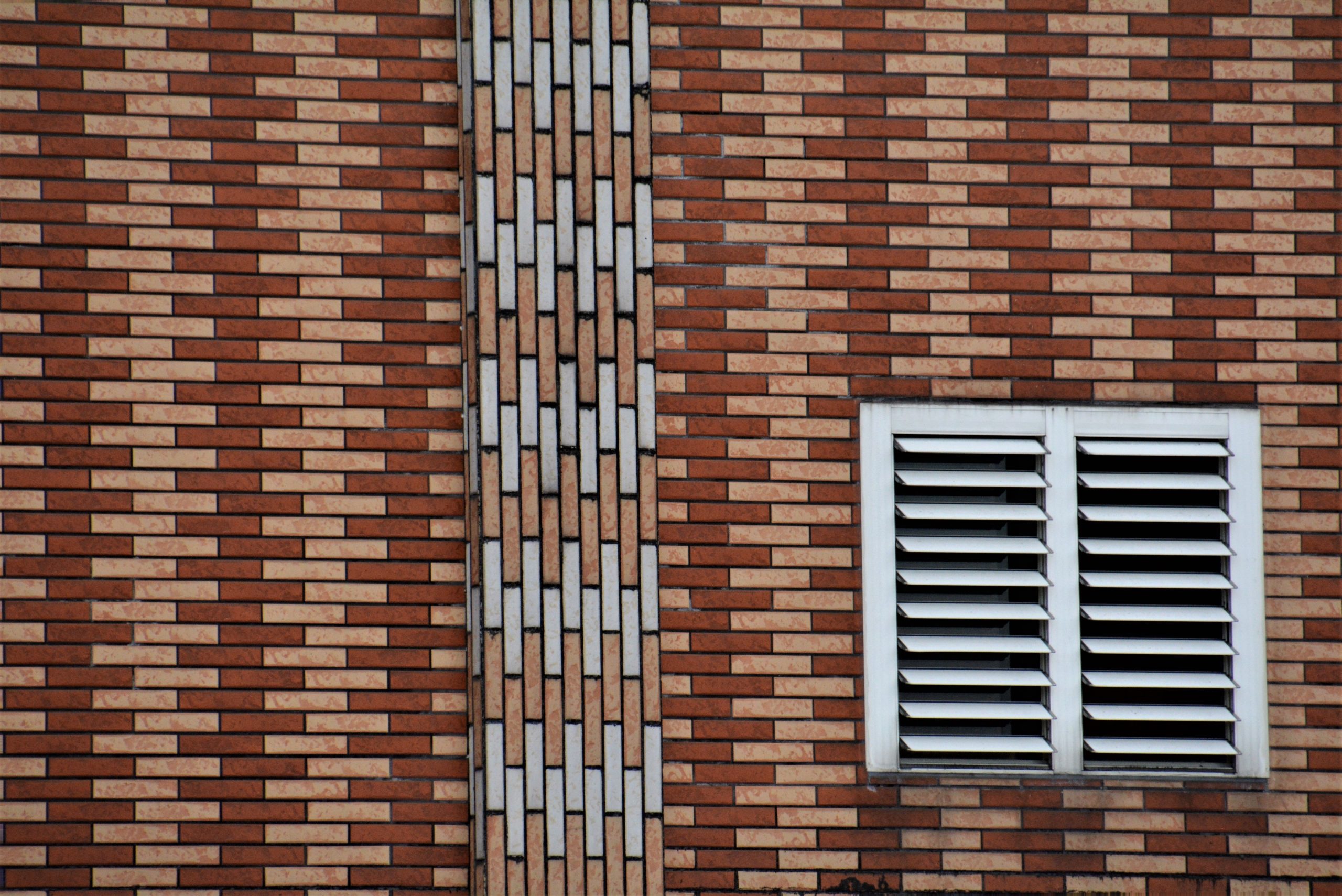 Mur en brique avec une grille de ventilation blanche