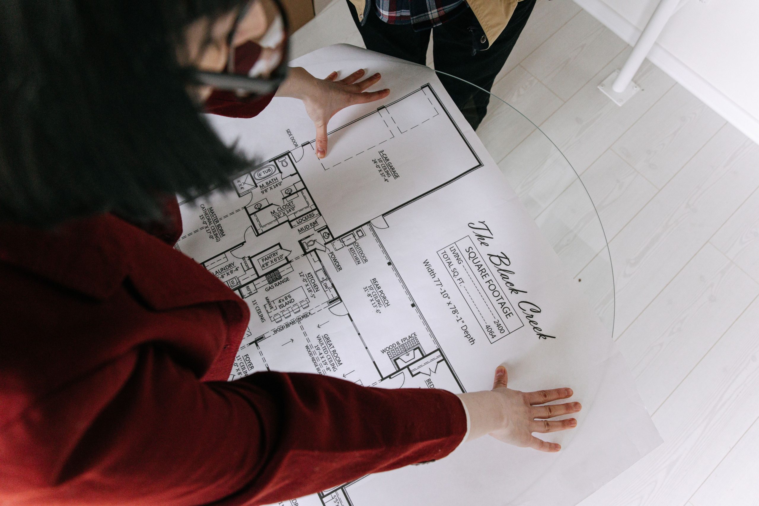 Femme examinant plans architecturaux sur table verre